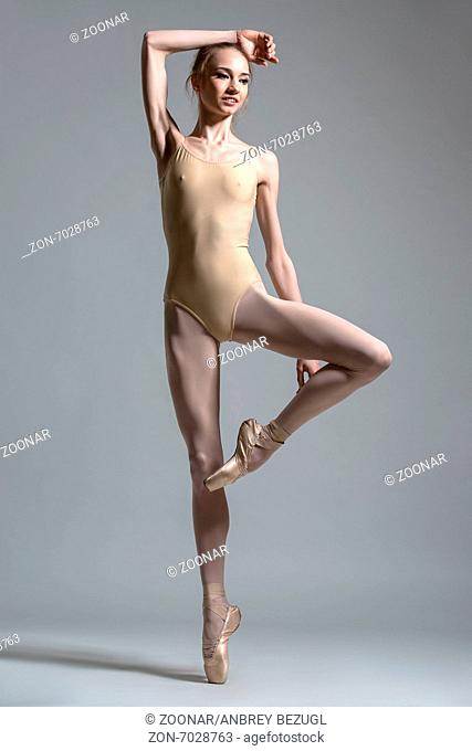 Fashion shot of a ballerina, which stands on one pointe, second leg tucked up