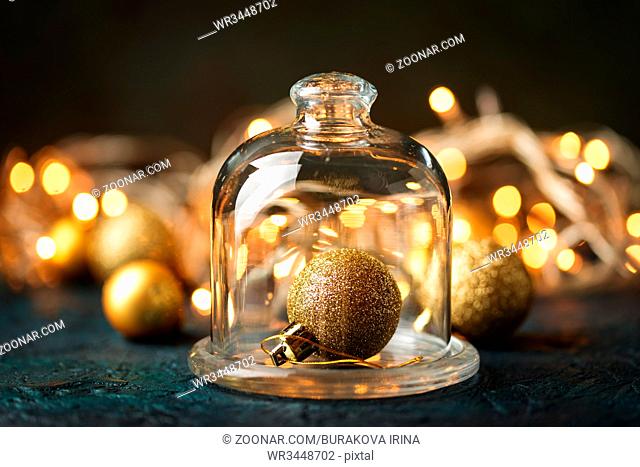 Golden christmas ball under the glass cap on the background of blurred lights