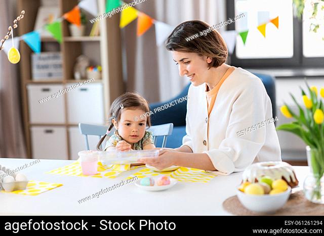 mother with child coloring easter eggs at home