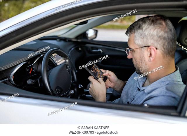 Man using smart phone GPS, sitting in his car