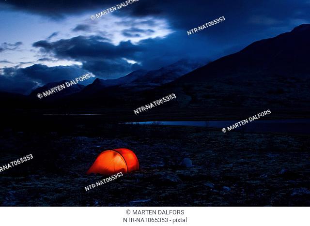 A well-lit red tent at a fjeld massif Rondane National Park Norway