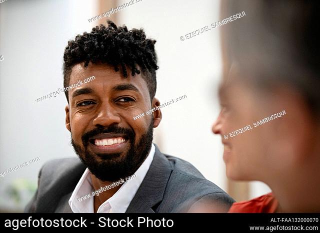 Smiling businessman listening to colleague