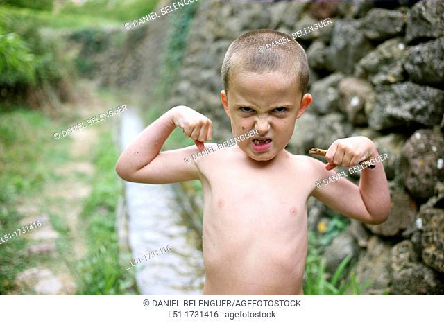 boy with angry face showing muscles without T-shirt, Ludiente, Castellón, Spain