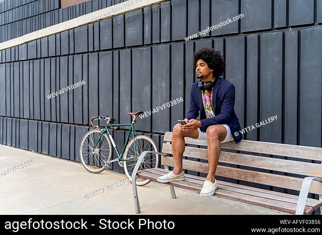 Stylish man with cell phone sitting on a bench