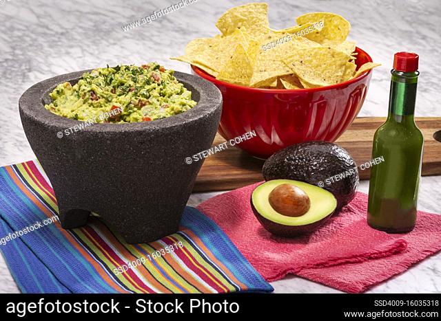 Guacamole and Chips with green hot sauce and a molcajete