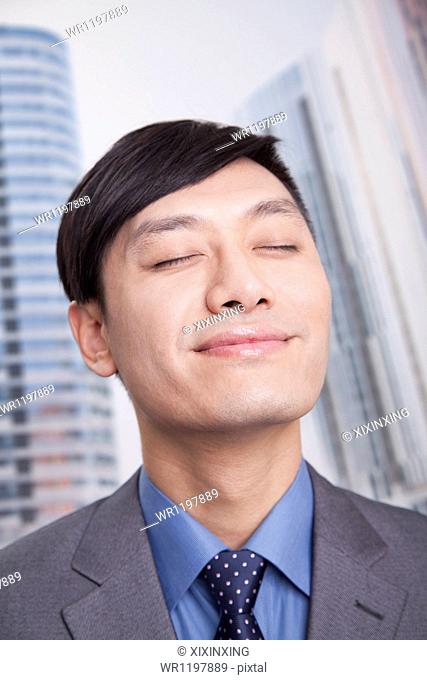 Young businessman with eyes closed and head back smiling, portrait