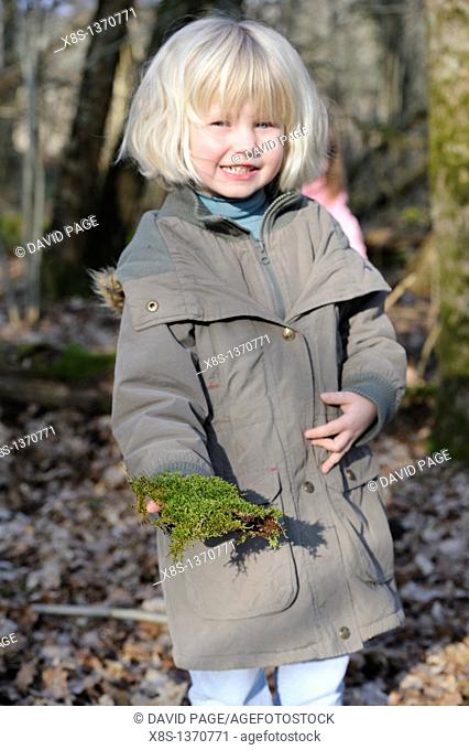 Five year old girl showing a piece of moss she has found on a nature walk