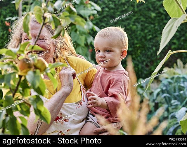 Grandmother holding toddler on hip in garden