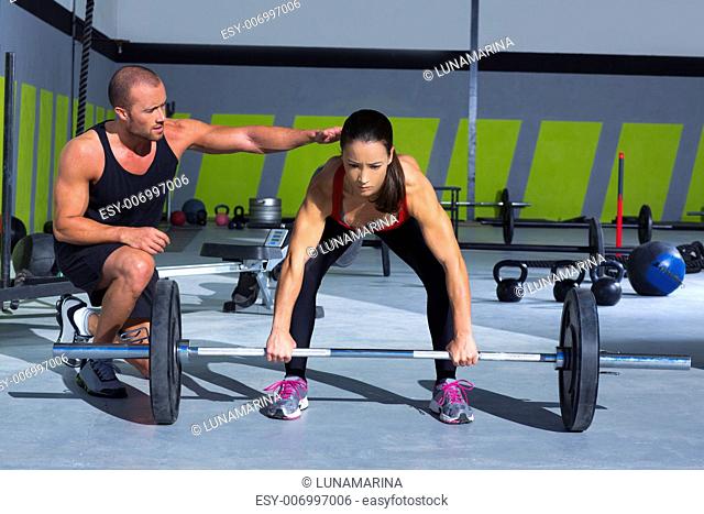 gym personal trainer man with weight lifting bar woman workout in crossfit exercise