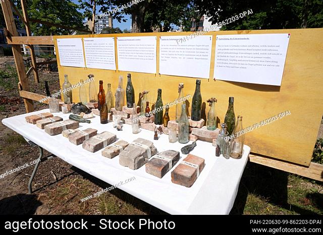 30 June 2022, Hamburg: Finds such as glass bottles stand on a table at the excavation site around the main church of St. Trinitatis in Altona