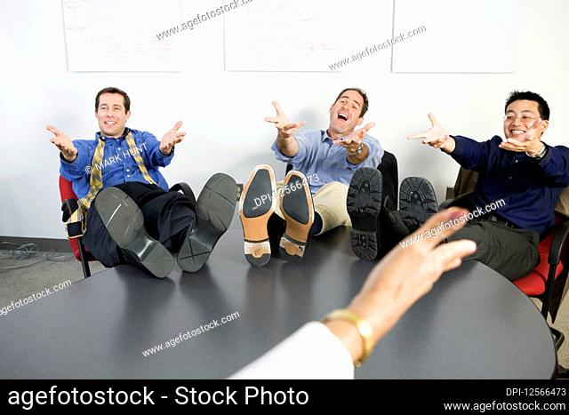 Businessmen gesturing with feet on desk