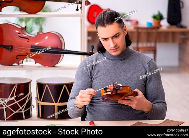 Young male repairman repairing violin in workshop