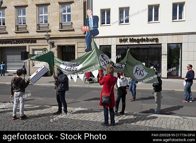 16 May 2020, Saxony-Anhalt, Magdeburg: A family with children shows a crocodile made of cloth that eats the constitution