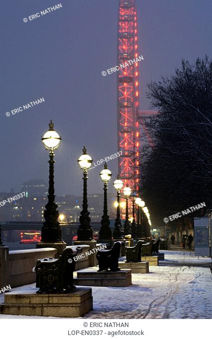 England, London, South Bank, An illuminated London Eye and River Thames embankment after a snowfall