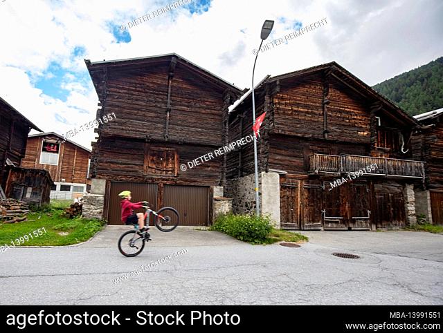 boy cycling, geschinen old town, obergoms, swiss alps