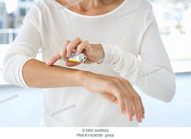 Woman applying ointment on her arm