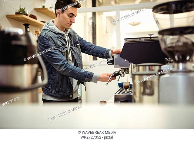 Hand of man holding portafilter under coffee machine