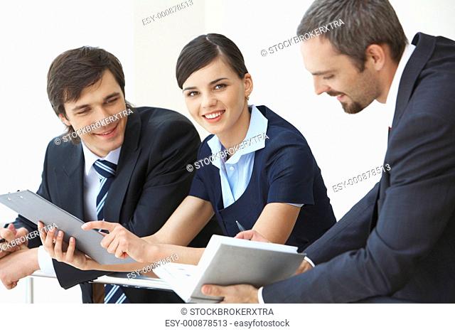 Pretty business lady looking at camera with smile surrounded by her co-workers