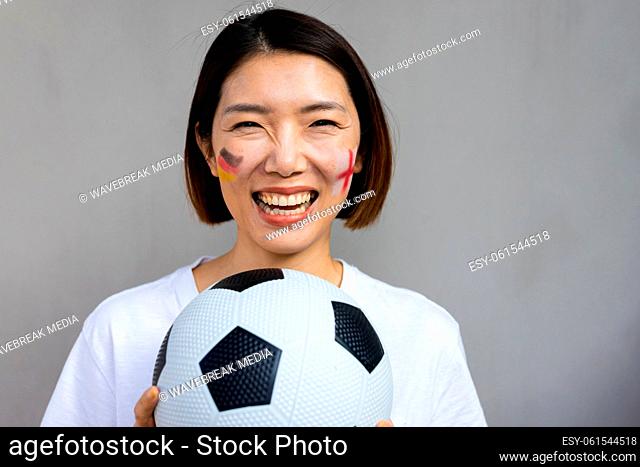 Portrait of happy asian woman with football and flags of germany and england on cheeks