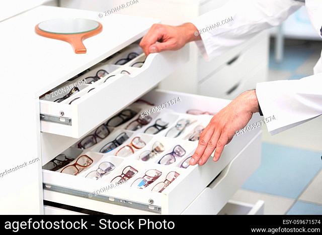 ophthalmologist hands close up, choosing glasses from a drawer in the optical store