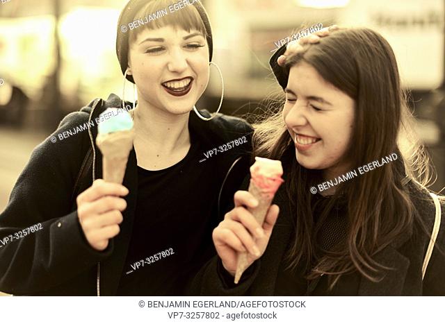 two lively friends with ice cream cones during warm winter day, in city Cottbus, Brandenburg, Germany