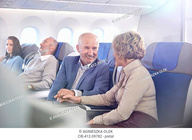 Affectionate mature couple holding hands on airplane