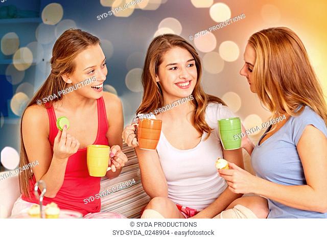 happy young women drinking tea with sweets at home