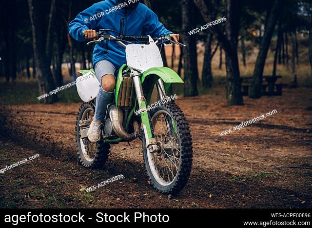 Teenage male rider riding on dirt track at forest during autumn