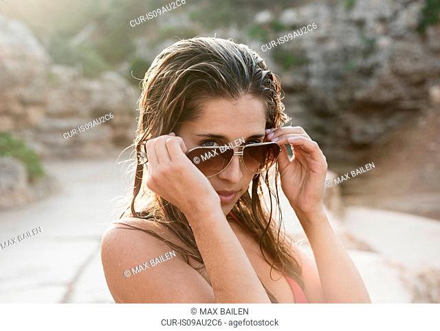 Portrait of young woman looking over her sunglasses
