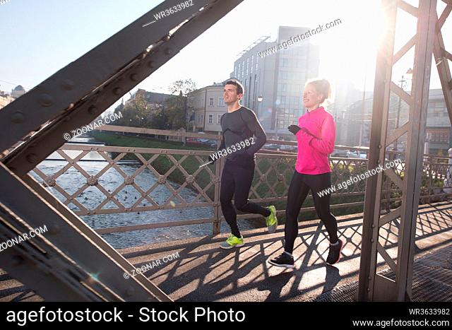 healthy young couple jogging in the city at early morning with sunrise in background