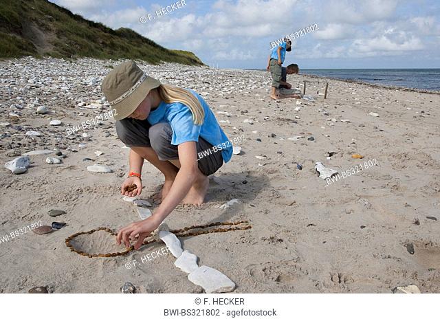 girl creating a sculpture of stones at the sand beach, Germany