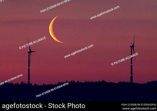 08 May 2021, Bavaria, Marktoberdorf: The crescent of the waning moon is behind two windmills shortly before sunrise. Photo: Karl-Josef Hildenbrand/dpa