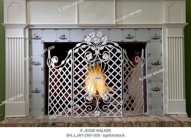 FIREPLACES: Straight view of classical mantel with tile surround, ornate metal fireplace screen with lattice and florals, brick hearth