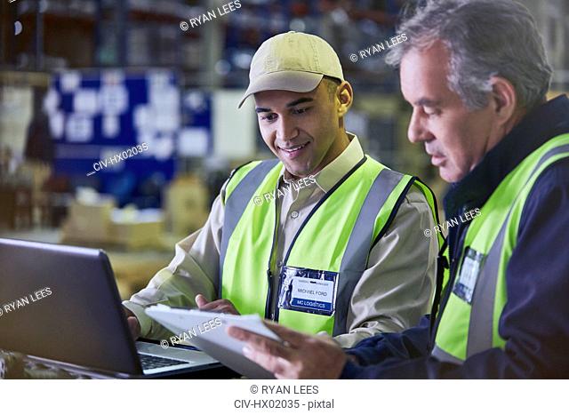 Workers with clipboard and laptop working in distribution warehouse