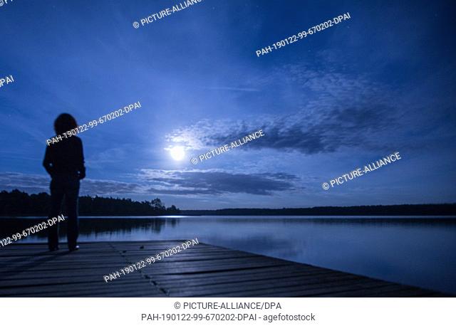 07 September 2017, Mecklenburg-Western Pomerania, Neukloster: A guest stands at full moon on a boat landing stage of the Seehotel at the Neuklostersee
