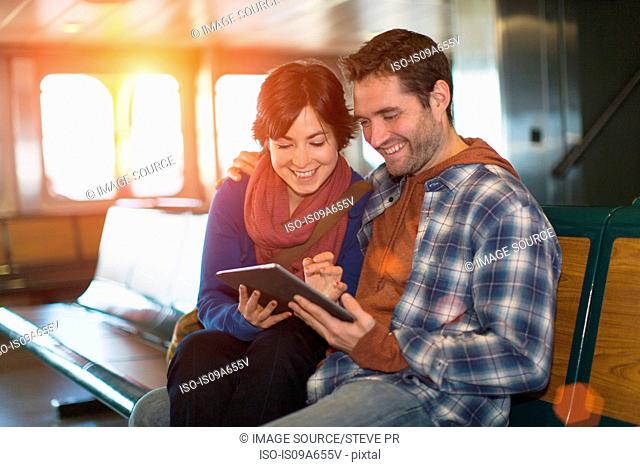 Couple using tablet computer on ferry