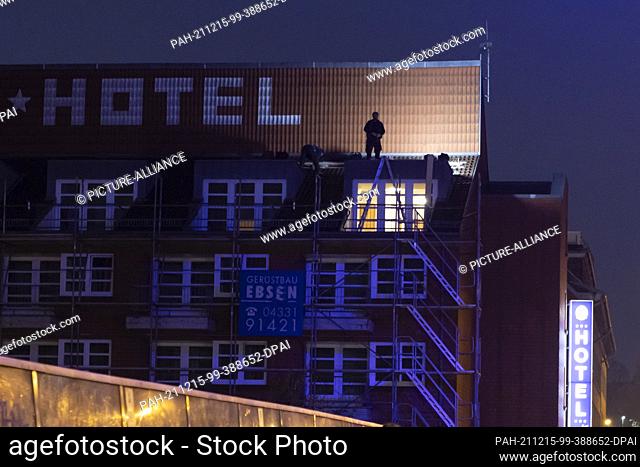 15 December 2021, Schleswig-Holstein, Kiel: The shadow of a construction worker standing on scaffolding is seen on the facade of a hotel in the early morning