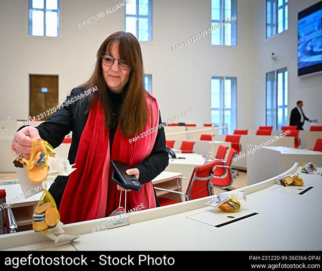 20 December 2023, Brandenburg, Potsdam: Katrin Lange (SPD), Brandenburg's Minister of Finance and for Europe, distributes chocolate coins on the tables of MPs...