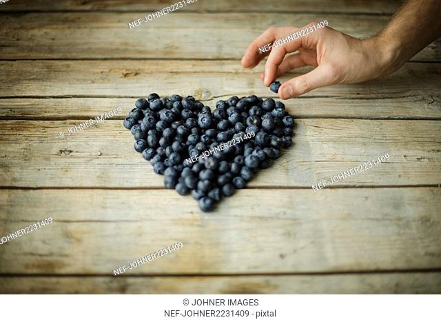 Hand making heart out of blueberries