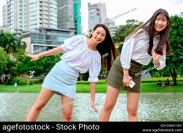 Portrait of two young beautiful Asian teenage girls together at the park