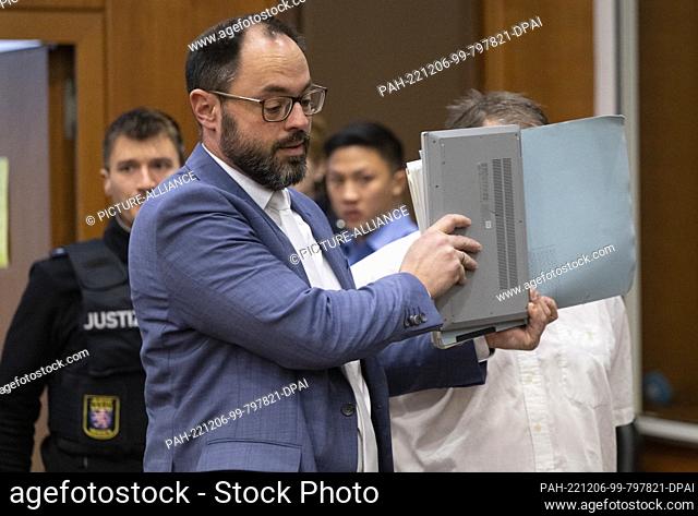 06 December 2022, Hessen, Frankfurt/Main: A defense attorney protects his client in the ""Boystown"" trial from the cameras of journalists with a file folder