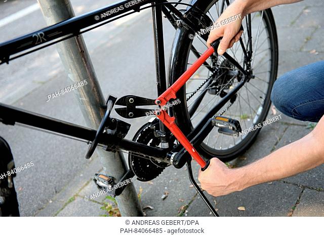 ILLUSTRATION - A man attempts to cut through a bike lock with bolt cutters in Munich, Germany, 14 September 2016 (staged scene)