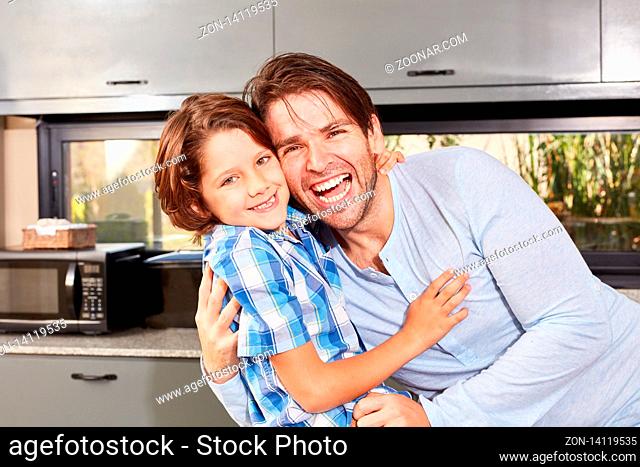 Lachender und stolzer Vater nimmt seinen Sohn in die Arme in der Küche