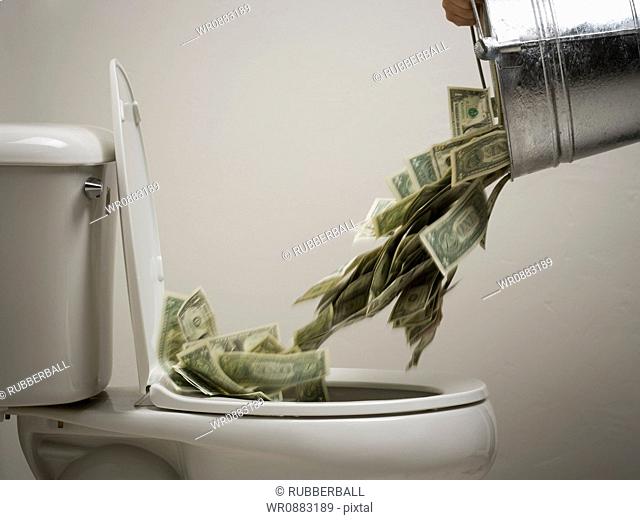 Person dumping money into a toilet bowl