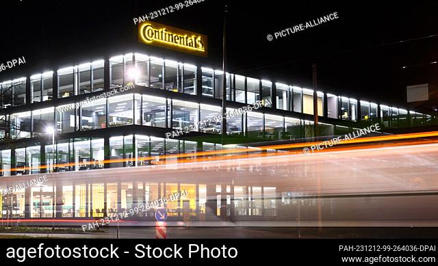 12 December 2023, Lower Saxony, Hanover: Lights shine in the new corporate headquarters of Continental AG, while passing streetcars leave trails of light