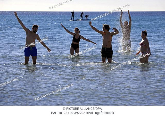31 December 2018, Spain, Palma: Peter, Joana, Martin, Mike, and Madalene from Poland seen seen swimming on Arenal beach during the sunny morning of the last day...