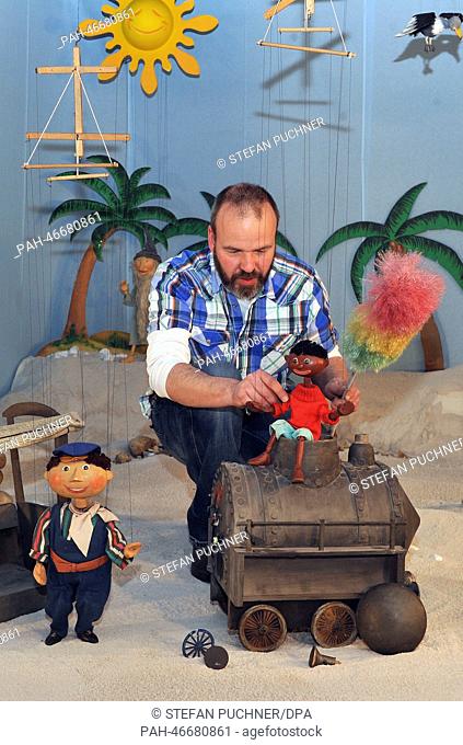 Hans Kautzmann sits with marionettes Lukas (L) and Jim Knopf as well as broken locomotive Emma in a desert scenario at the Puppenkiste (puppet chest) museum in...