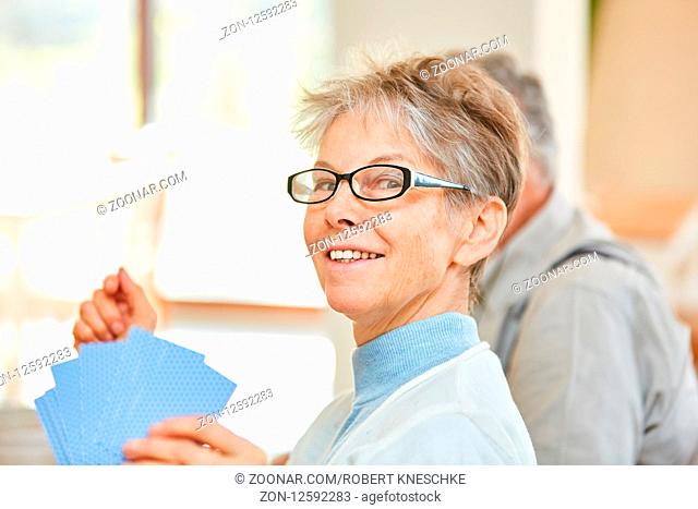 Vitale Senior Frau hat Spaß beim Kartenspiel mit Freunden im Seniorenheim