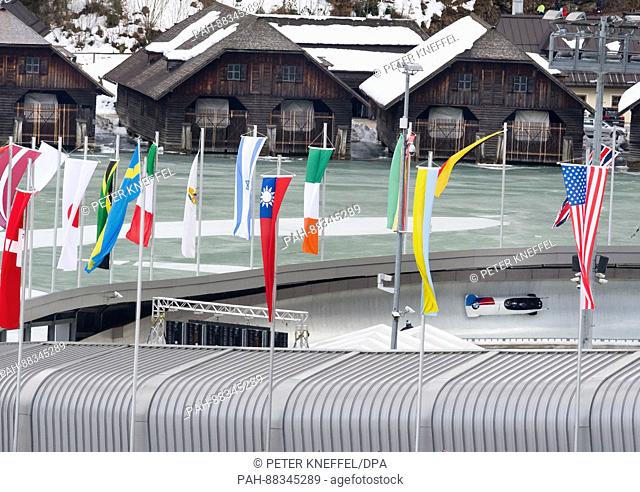 The four-person Bob with Steven Holcomb, Carlo Valdes, James Reed und Samuel McGuffie from the USA on the echo-curve lined with flags in Schoenau Am Koenigssee