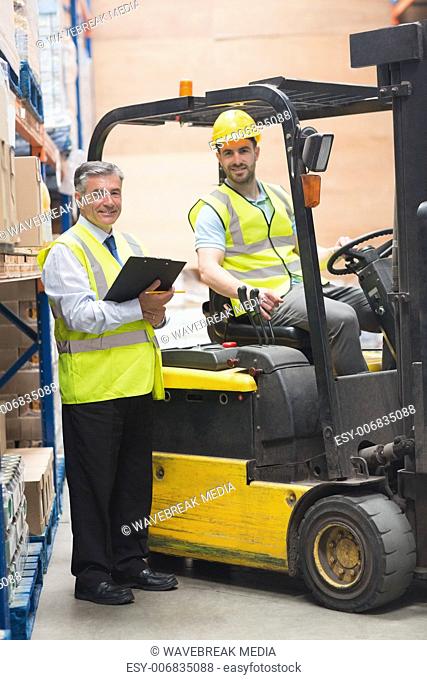 Driver operating forklift machine next to his manager